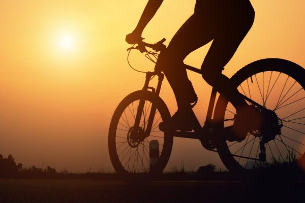 Road bike cyclist man cycling. Biking Sports fitness athlete riding bike on an open road to the sunset